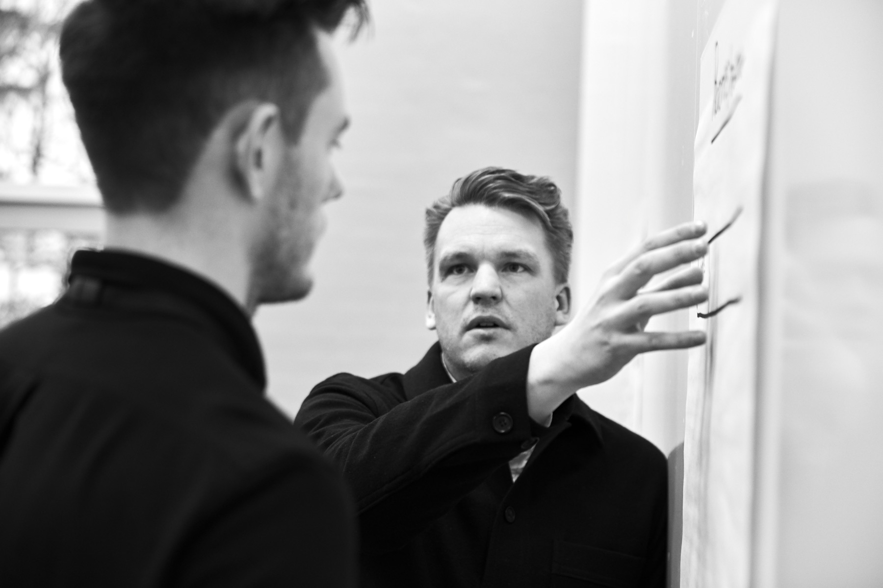 Martin i workshop, gestikulerer foran flipover med en kollega i forgrunden